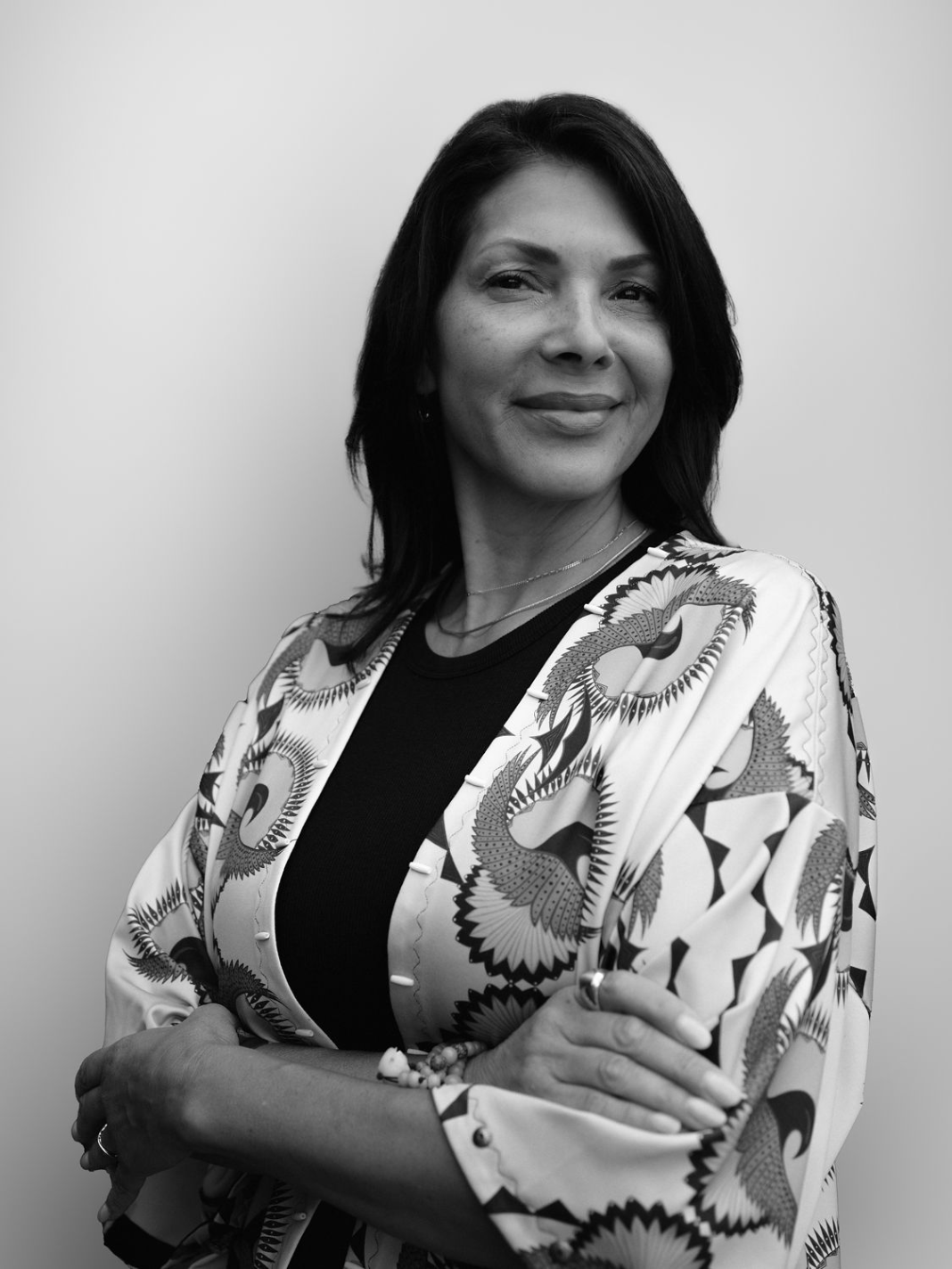 A black and white portrait of a smiling woman with her arms crossed.